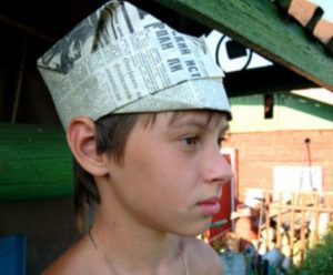 Boy with a newspaper hat with a visor