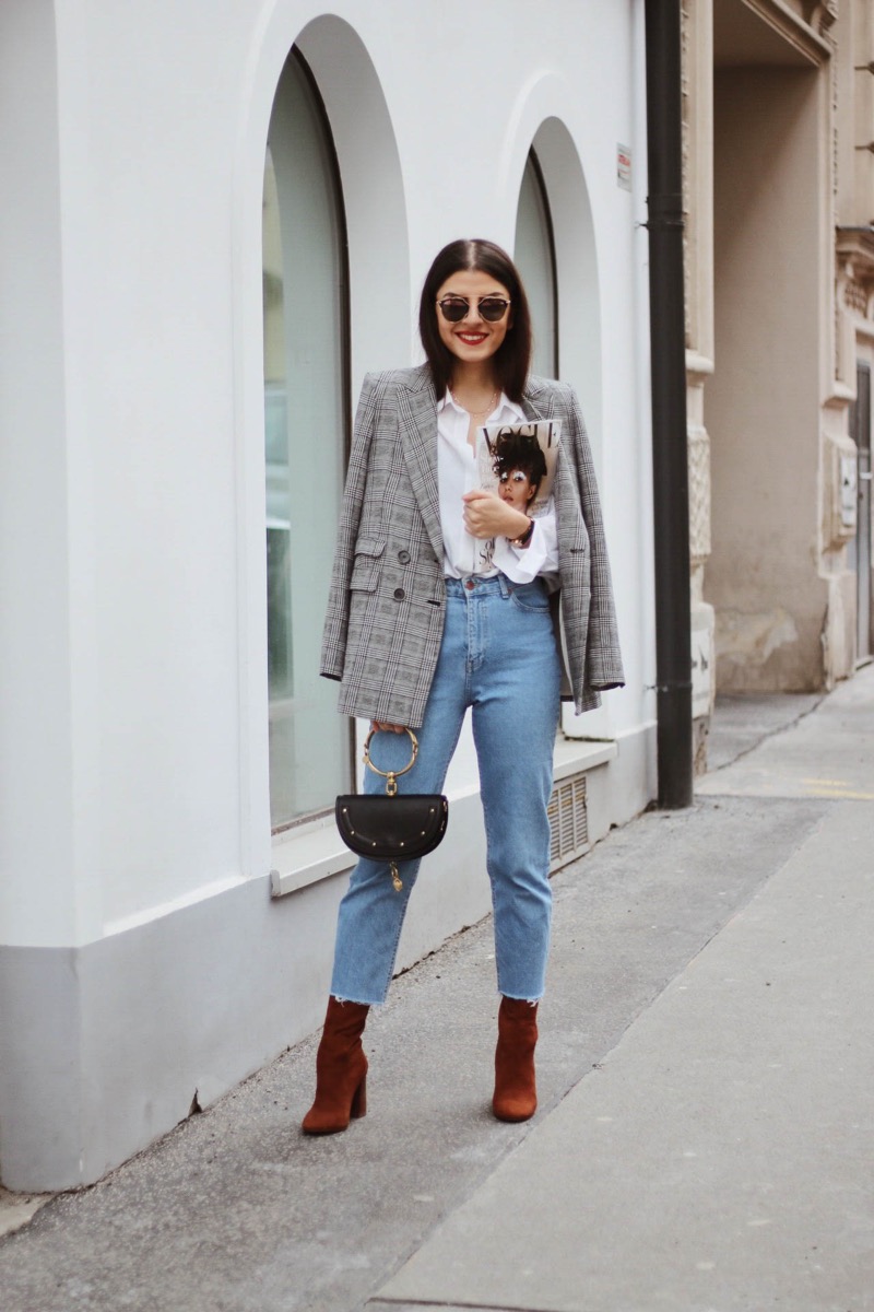 Chaqueta de cuadros gris, camisa holgada blanca y jeans rectos.