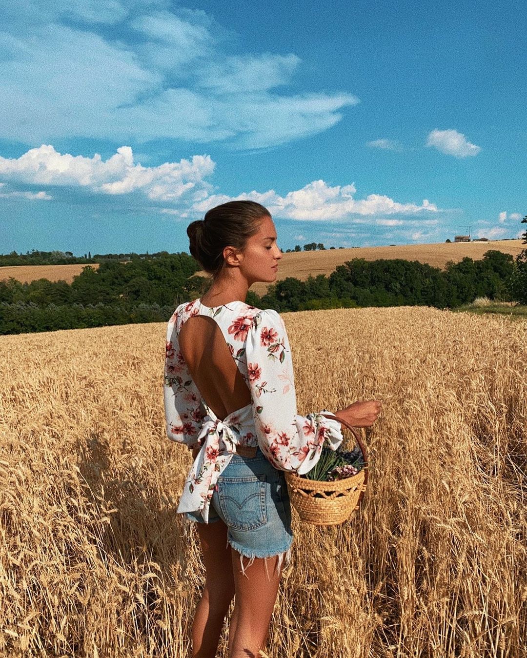 Meisje in een shirt met een open rug midden in een veld