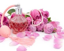 flesje-parfum-met-ketting-tussen-de-bloemblaadjes-van-een-bloem-op-een-witte-achtergrond-120307383