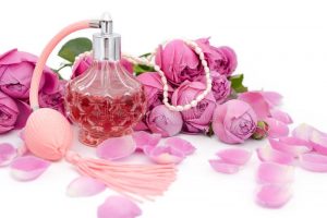 flesje-parfum-met-ketting-tussen-de-bloemblaadjes-van-een-bloem-op-een-witte-achtergrond-120307383